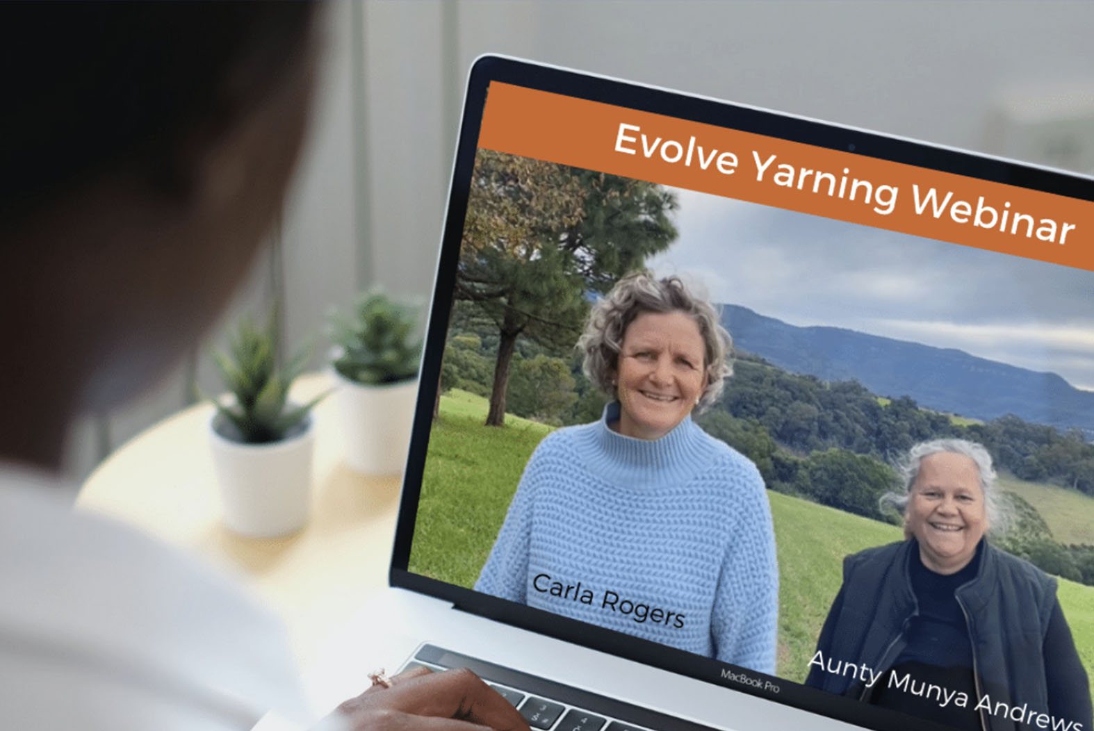 Over the shoulder perspective of a person on a laptop that is displaying an Evolve Communities Webinar